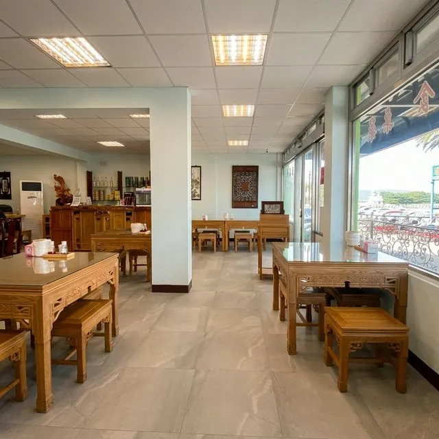 一樓用餐區,成排紅木桌椅與矮凳,窗外可見南寮漁港